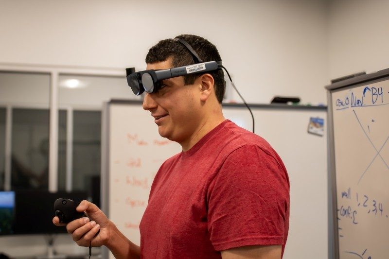 Brendan David-John wearing an eye-tracking device while holding and navigating its remote.