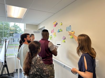 Members of team work together on research ideas using sticky notes posted to a wall.